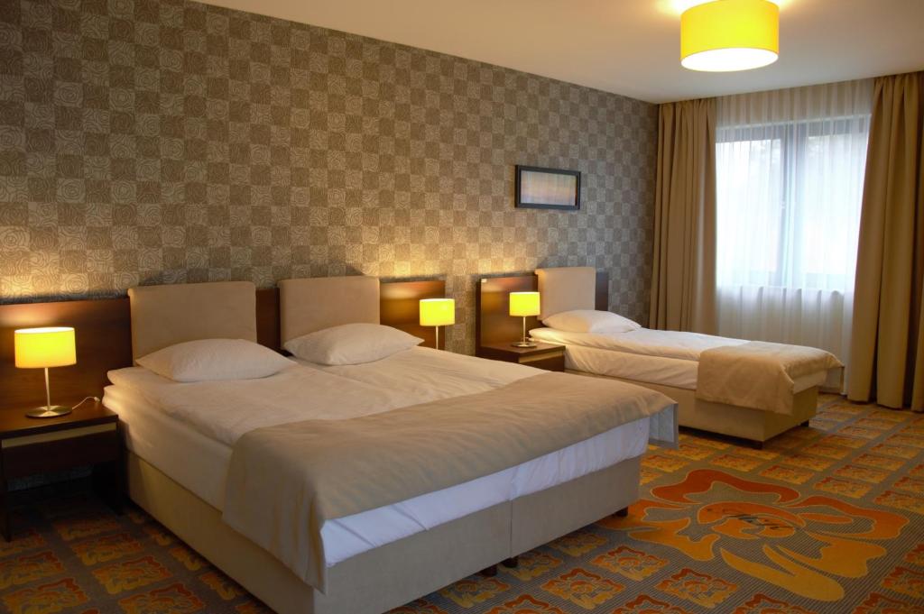 a hotel room with two beds and two lamps at Hotel Via Baltica in Łomża