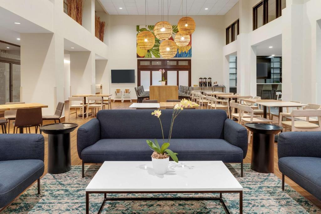 アラフエラにあるHampton By Hilton San Jose Airport Costa Ricaの青いソファ、テーブル、テーブルが備わるロビー