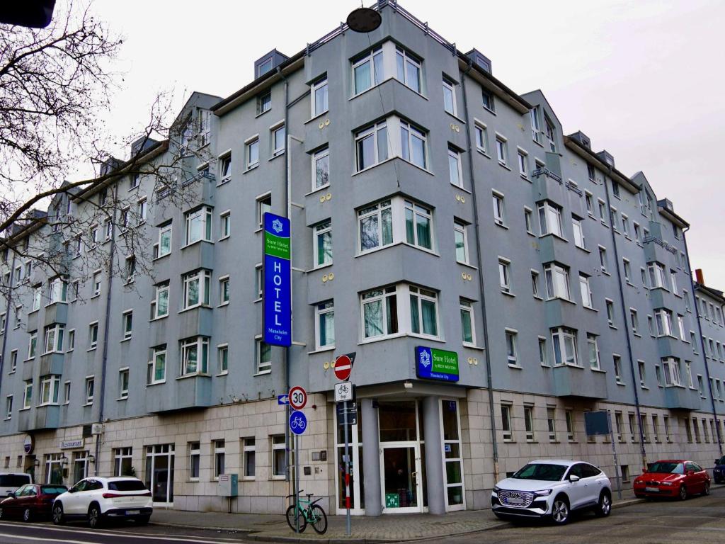un gran edificio gris con coches estacionados frente a él en Sure Hotel by Best Western Mannheim City, en Mannheim