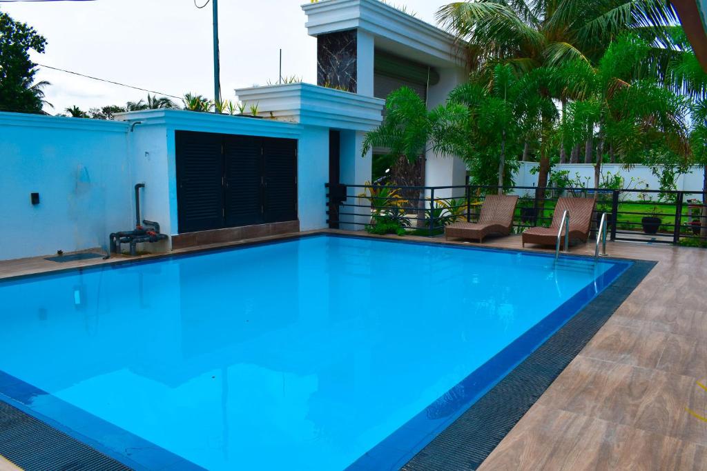 a large blue swimming pool in front of a house at CEYLON VILLA NILAVELI in Trincomalee