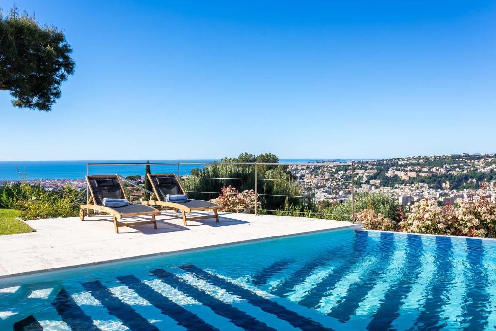 une piscine avec deux chaises et la vue sur la ville dans l'établissement VILLA ADRIANA VI4411 By Riviera Holiday Homes, à Nice