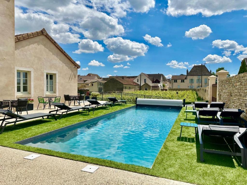 a swimming pool with chairs and tables in a yard at Hotel Particulier Les Rêveries du CLOS Vignes &Spa Adult Only in Pommard