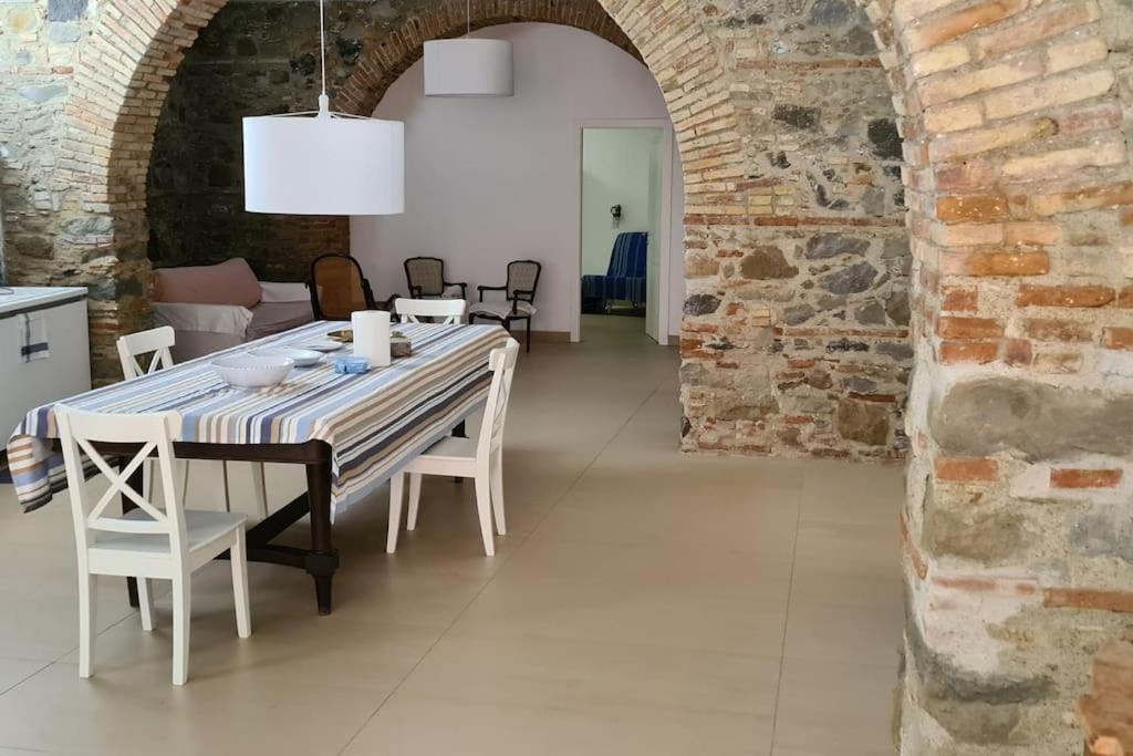 a dining room with a table and a brick wall at A 20 passi dal mare in Giardini Naxos
