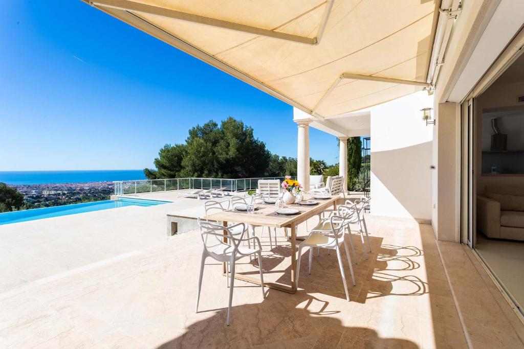 une salle à manger avec une table et des chaises sur un patio dans l'établissement VILLA SAVANNAH VI4356 By Riviera Holiday Homes, à Nice
