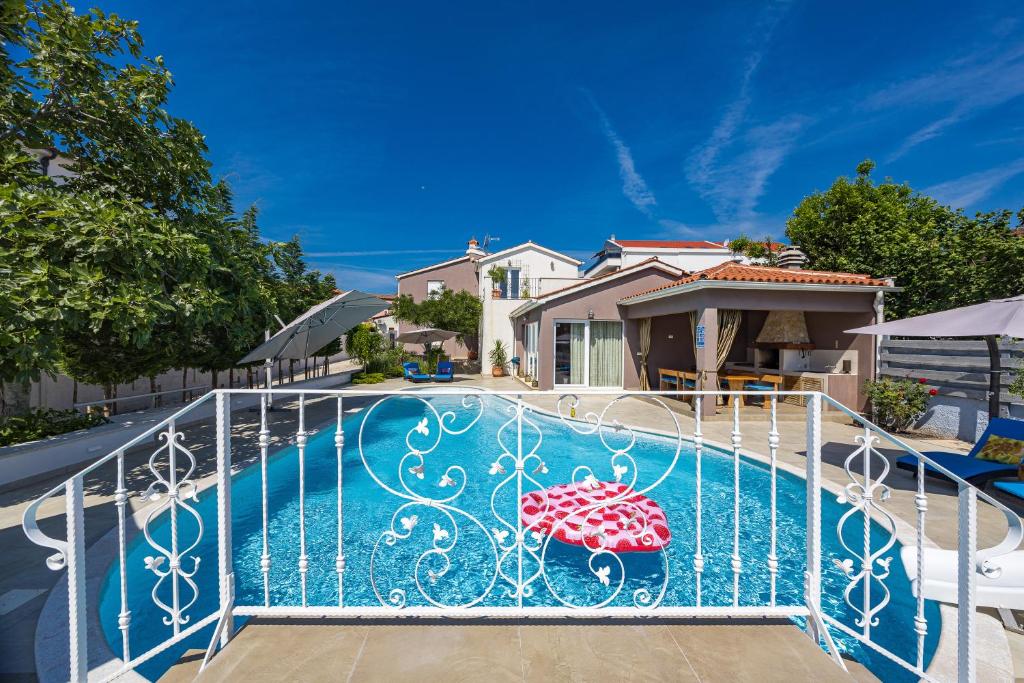 a swimming pool with an iron gate with an umbrella at Five bedroom villa Emily with pool in Medulin in Medulin