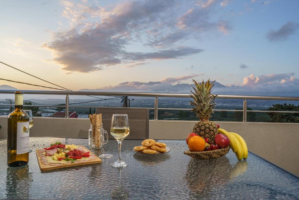 a table with a glass of wine and fruit on it at Leonidas Family Apartment 1 in Pómbia
