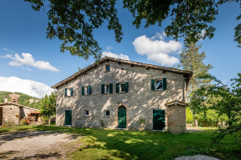 an old stone building with green doors on a green yard at Verde Immenso - Pool BBQ Relax in Molino Abbadia