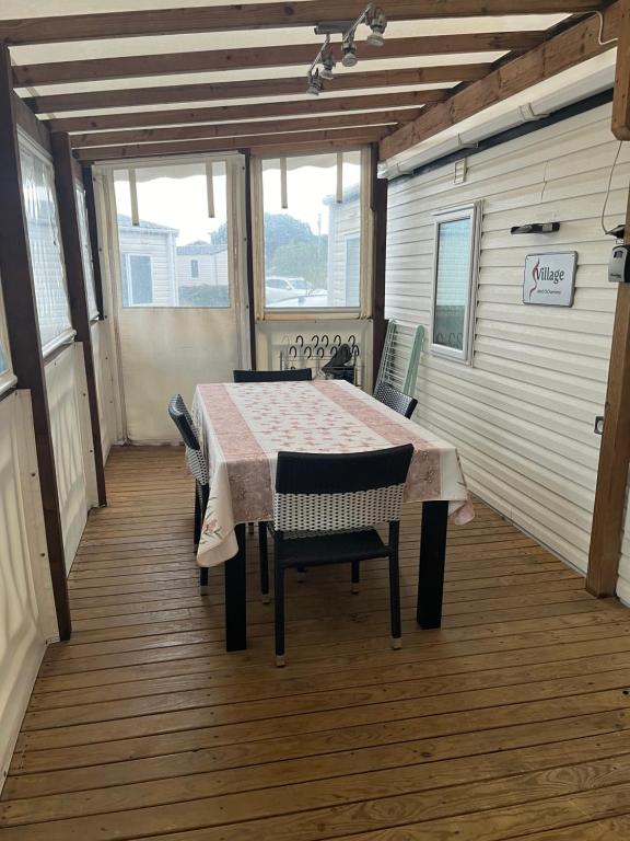 a room with a table and chairs on a porch at Mobil Home avec WIFI -6-8 Personnes in Lattes