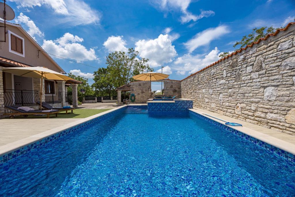 a swimming pool in front of a stone wall with an infinity at Family retreat House Begonija with pool and BBQ in Burići