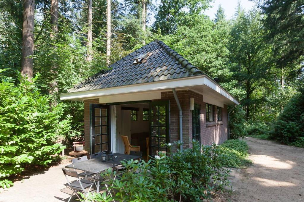 uma pequena casa com um alpendre na floresta em Bos Huisje em Putten