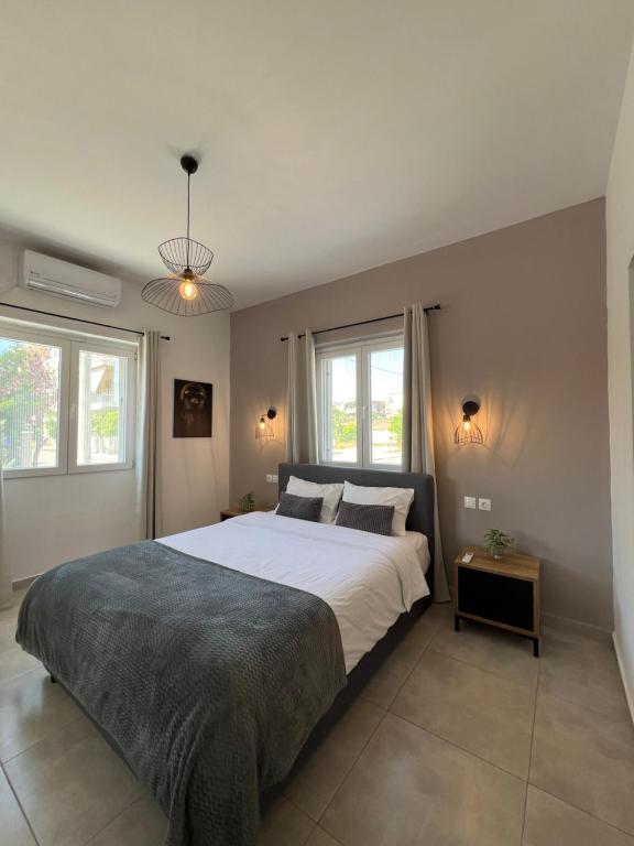 a bedroom with a large bed and two windows at Elefsinian Mysteries Apartments in Elefsina