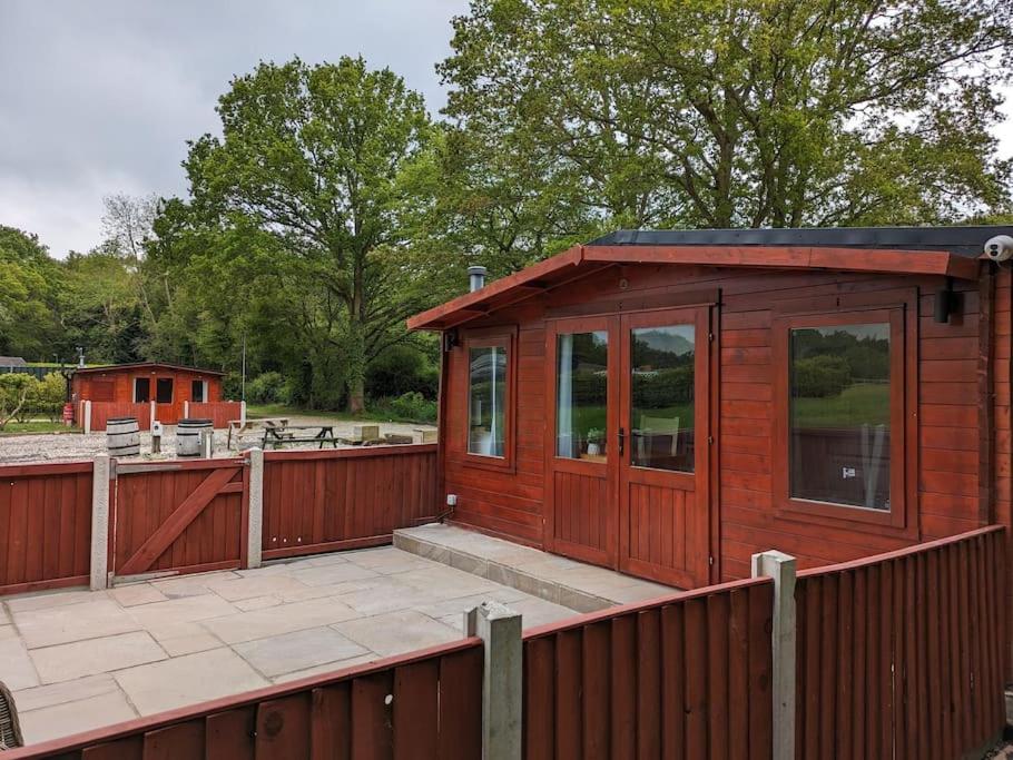 a small red building with a wooden fence at Meadow Lodge in Billericay