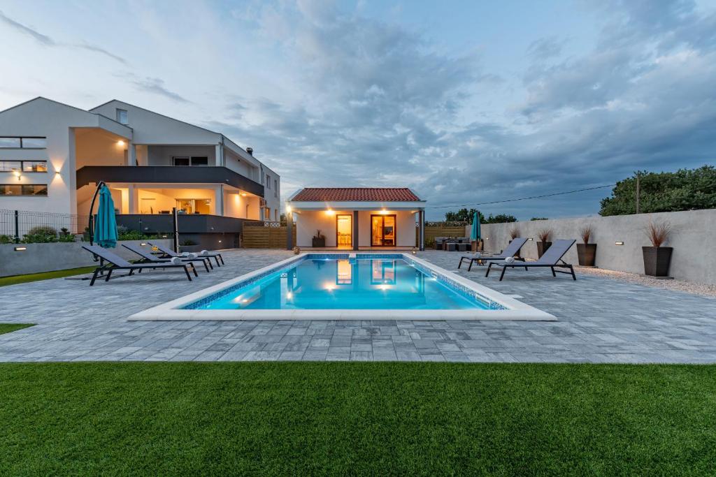 Un patio trasero con piscina y una casa. en Villa Zeleni gaj ZadarVillas, en Donje Raštane
