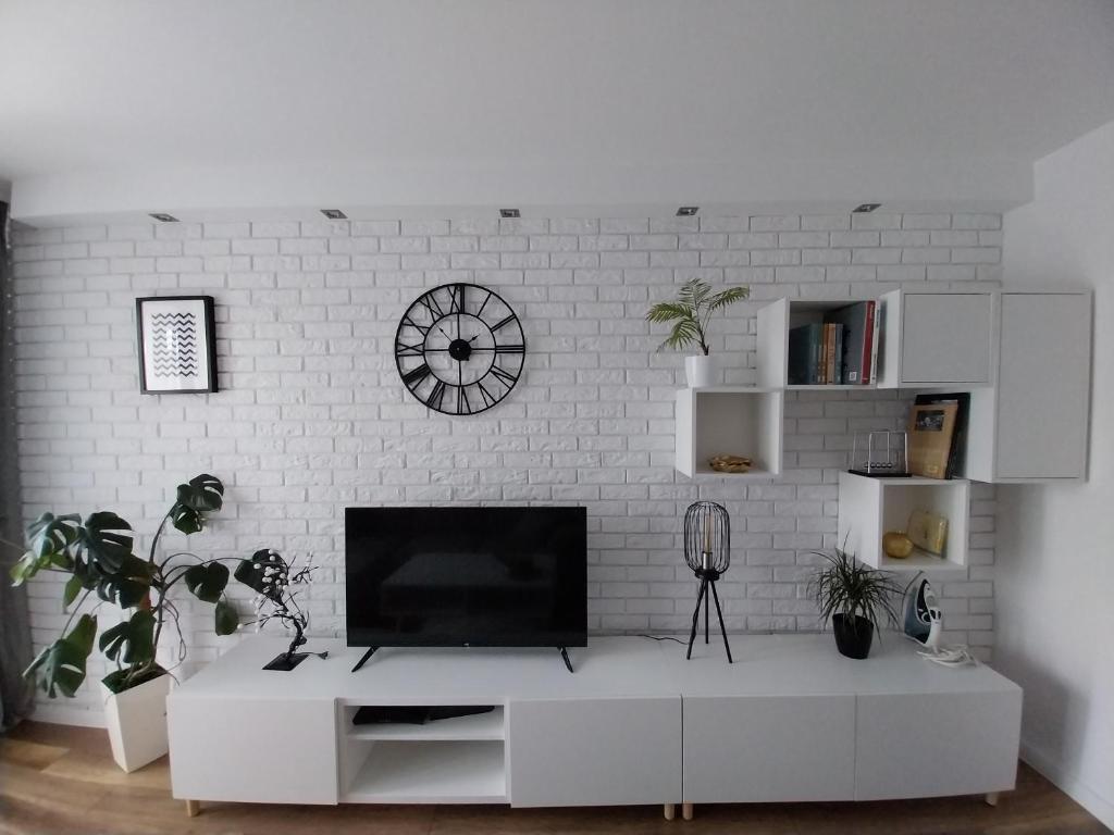 a living room with a tv on a white brick wall at Apartament na Sadowej in Sanok