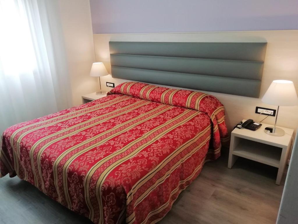 a hotel room with a bed with a red bedspread at Hotel Kristall in San Donà di Piave