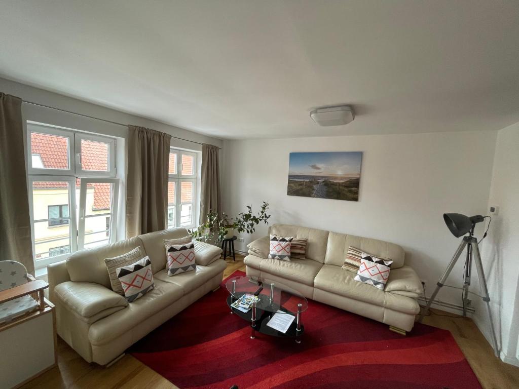 a living room with two couches and a red rug at Five O - Familie Meeresleuchten - 3 Schlafzimmer in Wismar