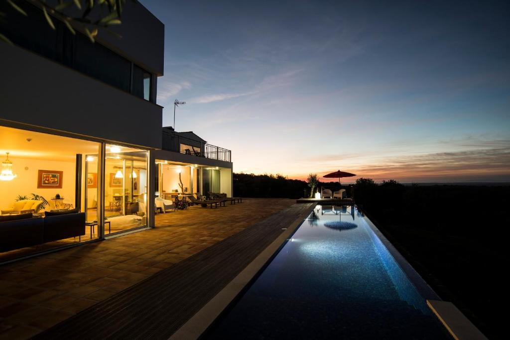 uma casa com piscina em frente a um edifício em A Serenada Enoturismo em Grândola