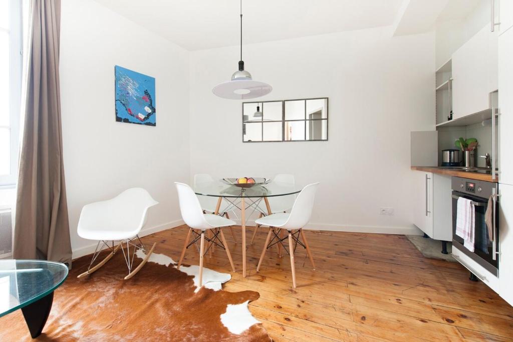 une salle à manger avec une table en verre et des chaises blanches dans l'établissement Le Sage, à Toulouse