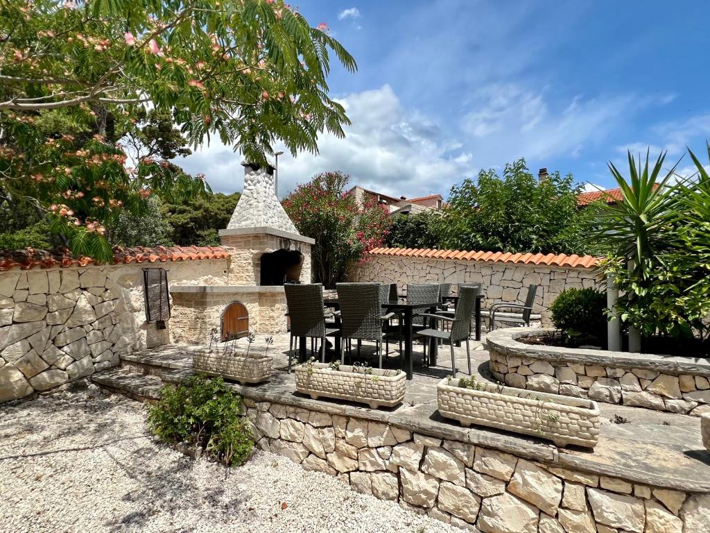 a patio with a table and chairs and a stone wall at Vila Vera Seafront Apartments in Sumartin