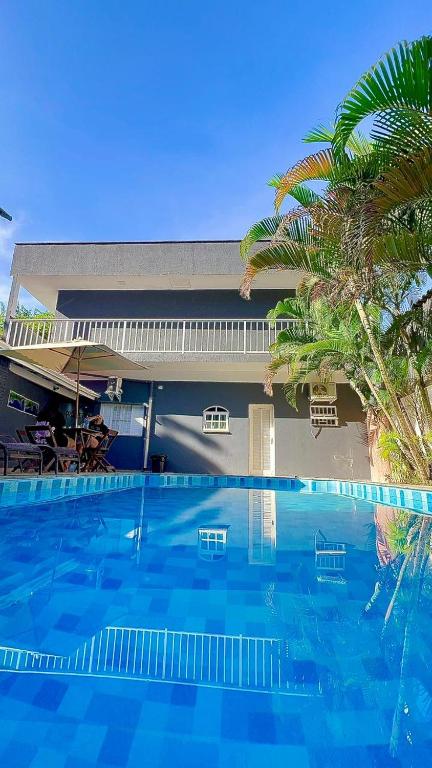 a large blue swimming pool in front of a house at Brisa mar pousada in Ubatuba