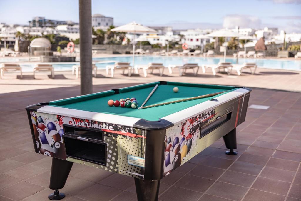 a pool table sitting next to a swimming pool at Caybeach Papagayos in Playa Blanca