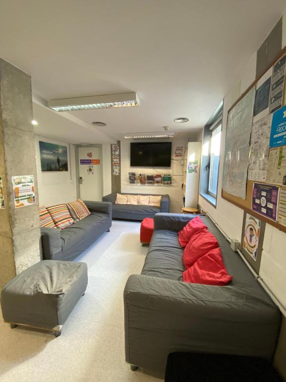 una gran sala de estar con sofás y TV de pantalla plana. en Scout Madrid Hostel, en Madrid