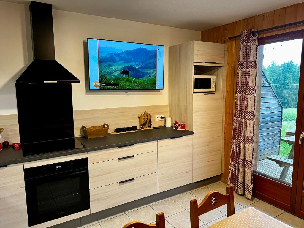 une cuisine avec une télévision à écran plat au mur dans l'établissement Chalet rénové 6 pers, TV connectée, WiFi, parking, animaux admis - FR-1-504-480, à Saint-Étienne-en-Dévoluy