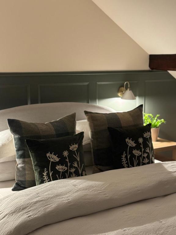 a bedroom with a bed with a green headboard and pillows at Chestnut Cottage Ravensworth in Richmond