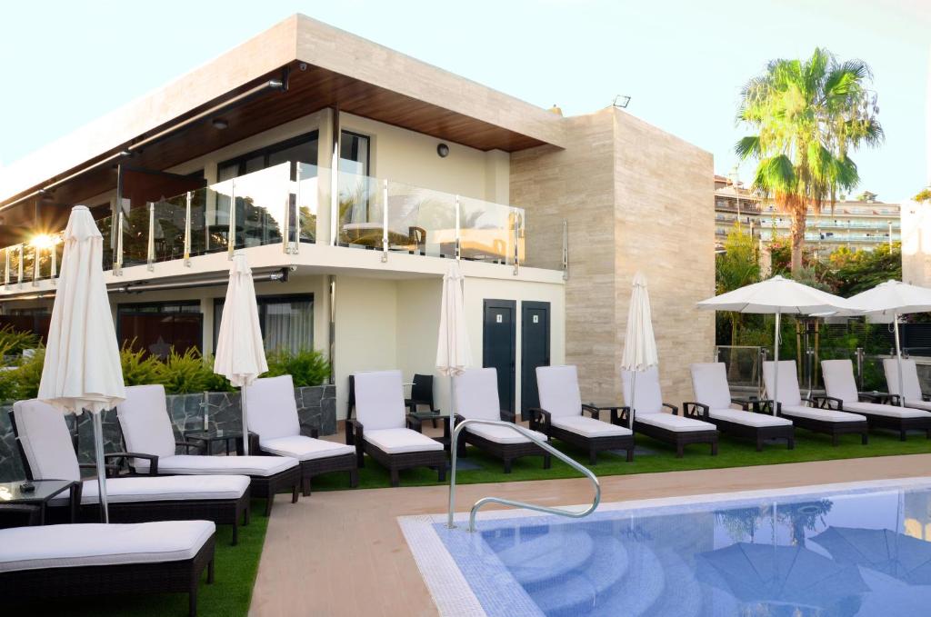 a pool with chairs and umbrellas next to a building at La Cataleya in San Agustin