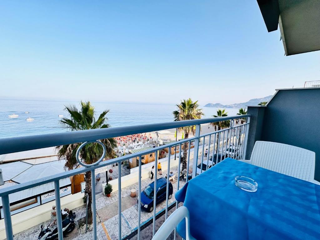 a balcony with a blue table and a view of the beach at Maniel Beach Hotel in Letojanni