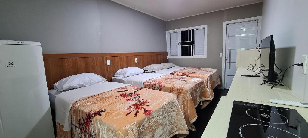 a hotel room with two beds and a television at Locapart Hospedagens in Chapecó