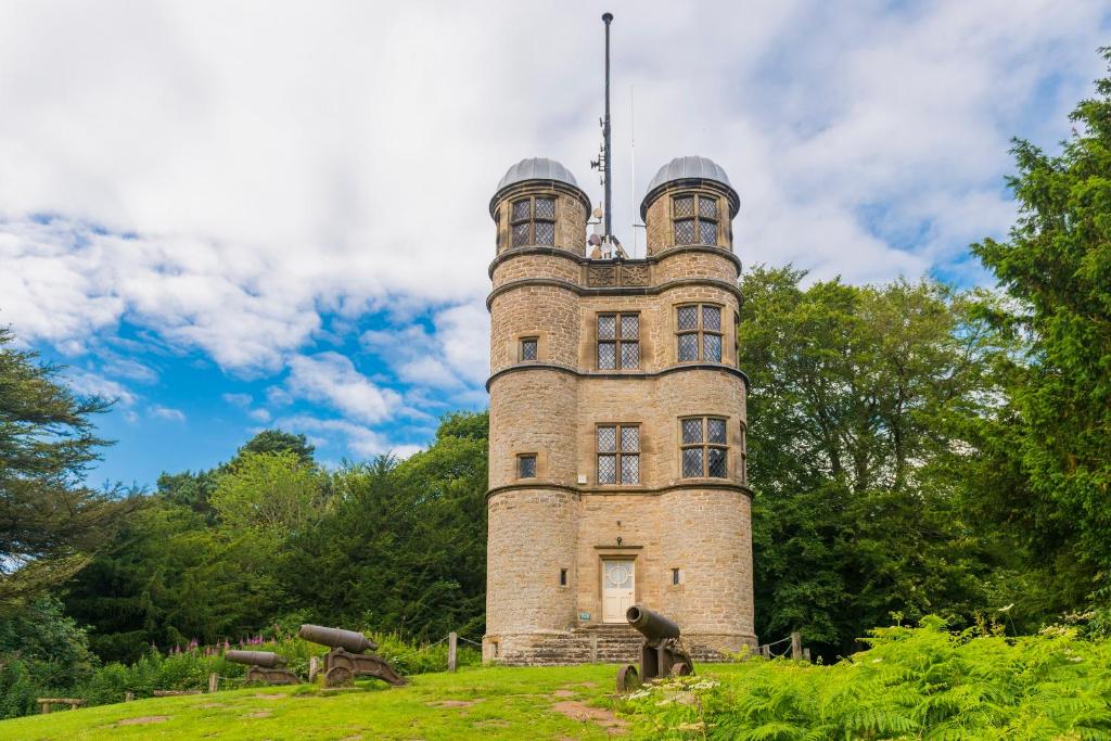 a tall brick tower on top of a hill at The Hunting Tower in Baslow
