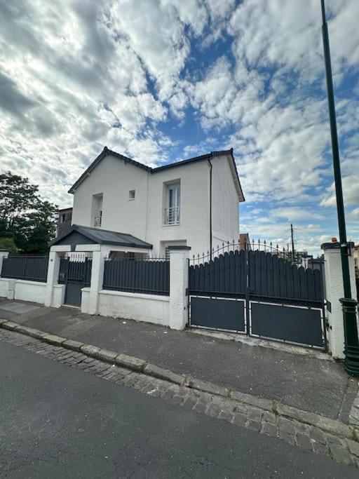 una casa blanca con una valla delante en Luxueuse Villa Neuve avec Jardin, en Colombes