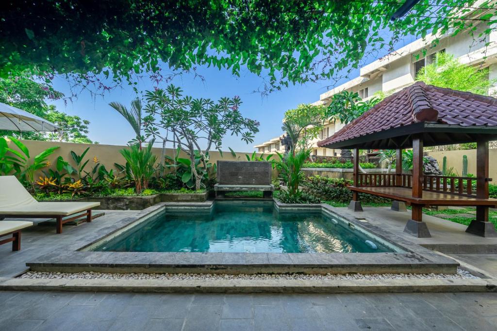 努沙杜瓦Aradhia Villa Nusa Dua的庭院内的游泳池,配有长凳和遮阳伞