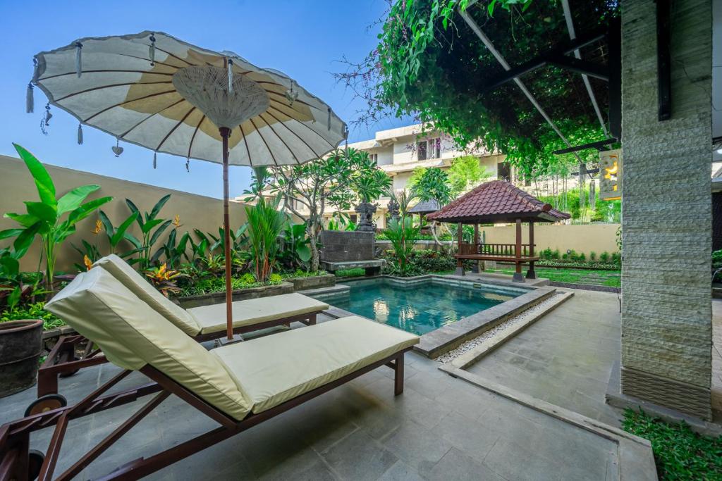 a chair and an umbrella next to a swimming pool at Aradhia Villa Nusa Dua in Nusa Dua