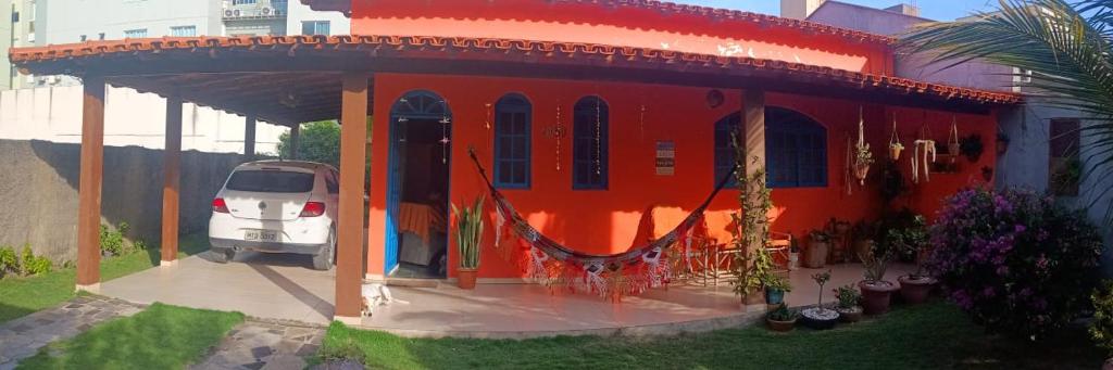 una casa rossa con una macchina parcheggiata di fronte di Casa Castelhanosbeach - 100 m do mar a Anchieta