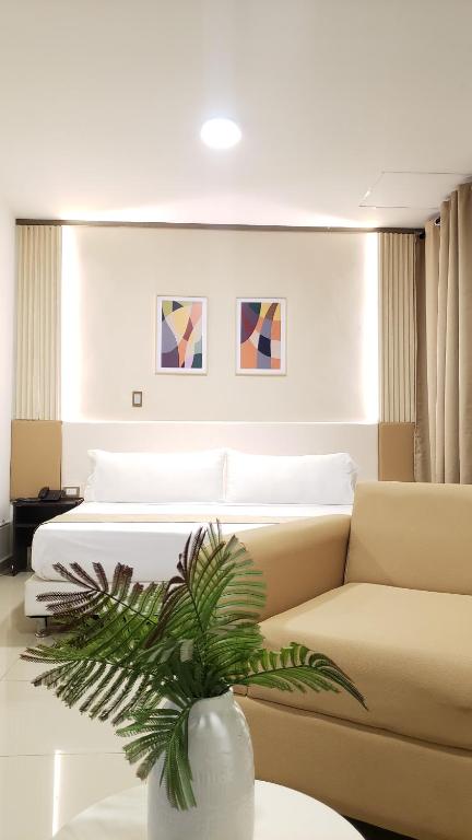 Hotel Suite Center Pereira في بيريرا: غرفة نوم بسرير و مزهرية بها نبات