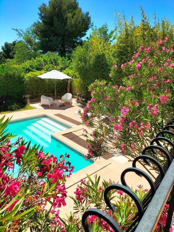 - une piscine avec des chaises et des fleurs roses dans l'établissement Vacances, à Carnoux-en-Provence