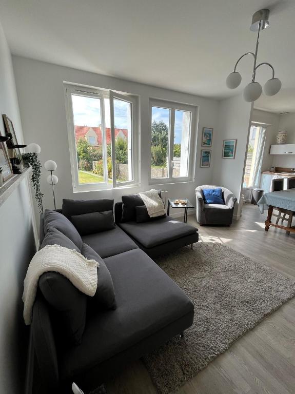un salon avec un canapé noir et un salon avec des fenêtres dans l'établissement Maison de ville à la mer très bien équipée proche centre avec commerces, à Plouescat