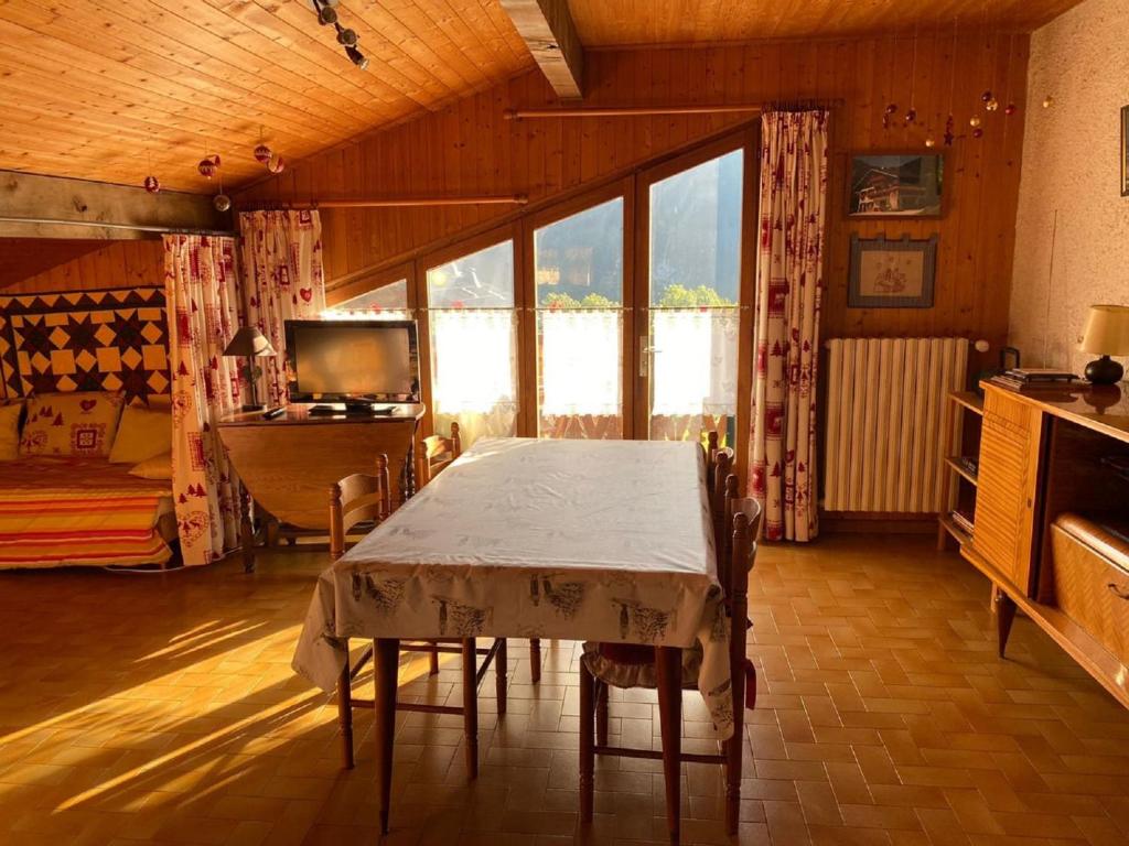 une salle à manger avec une table avec des chaises et une télévision dans l'établissement Chalet 2 pièces pour 5 pers. près des remontées, cuisine équipée, WIFI, parking, animaux admis - FR-1-676-176, à Châtel