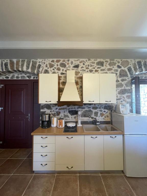 a kitchen with white cabinets and a stone wall at Traditional Cottage in Veliés