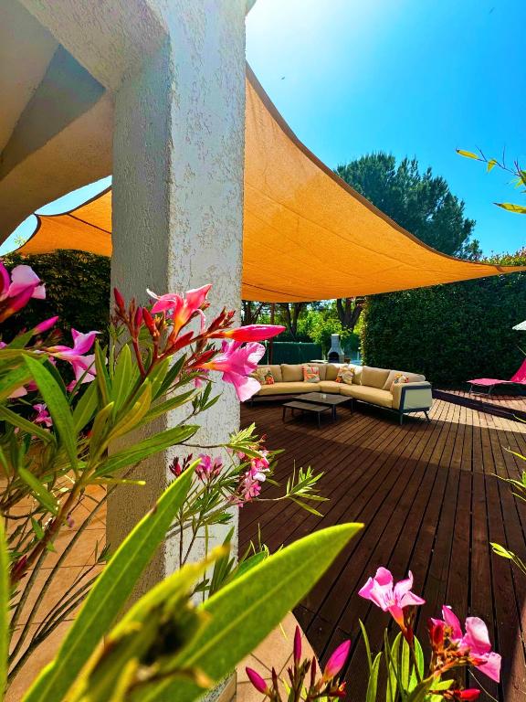 un patio avec un canapé sur une terrasse fleurie dans l'établissement Campo Vecchio Dracena et Piscine, à Ghisonaccia