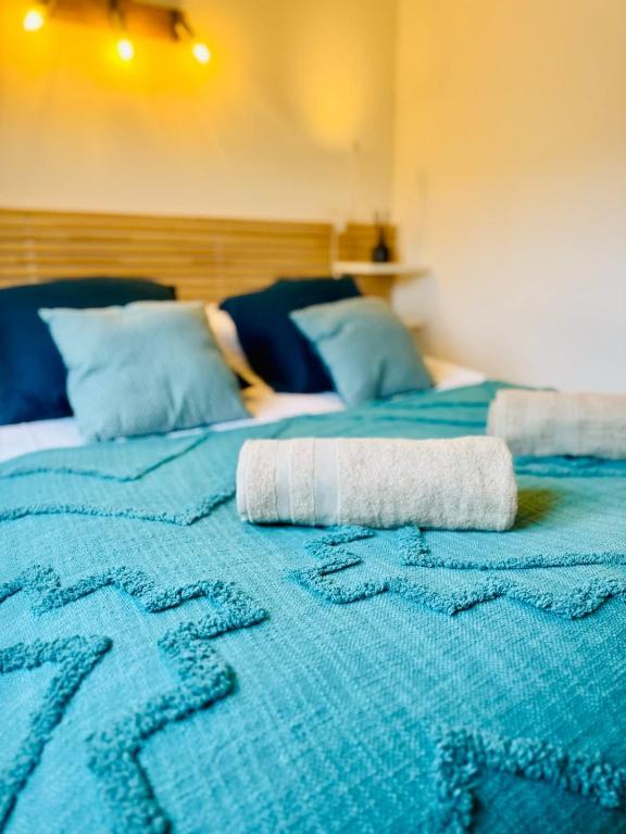 une serviette enroulée sur une couverture bleue sur un lit dans l'établissement Les Sarments charme de l'Ancien renové et au calme, à Mus