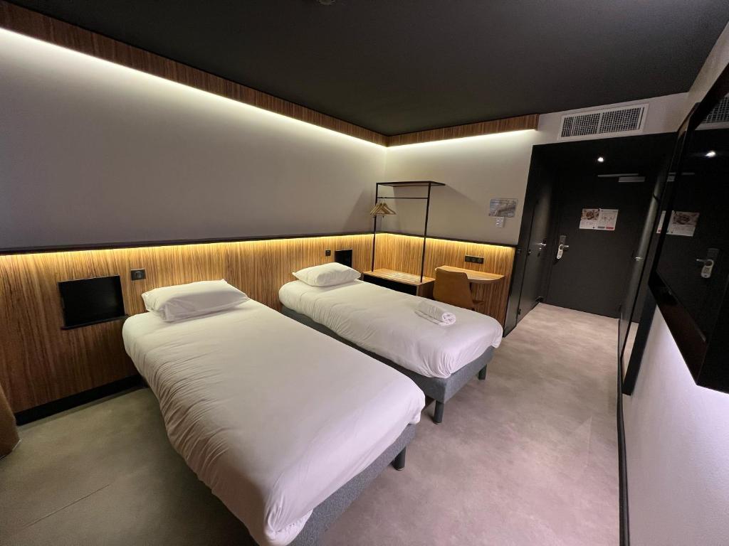 a room with two beds and a desk in it at B&B HOTEL Clermont-Ferrand A71-A75 La M&eacute;ridienne in Clermont-Ferrand