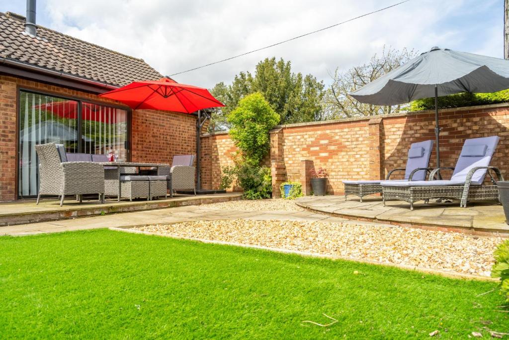 a patio with chairs and a table and an umbrella at One Lazy Duck in Heacham