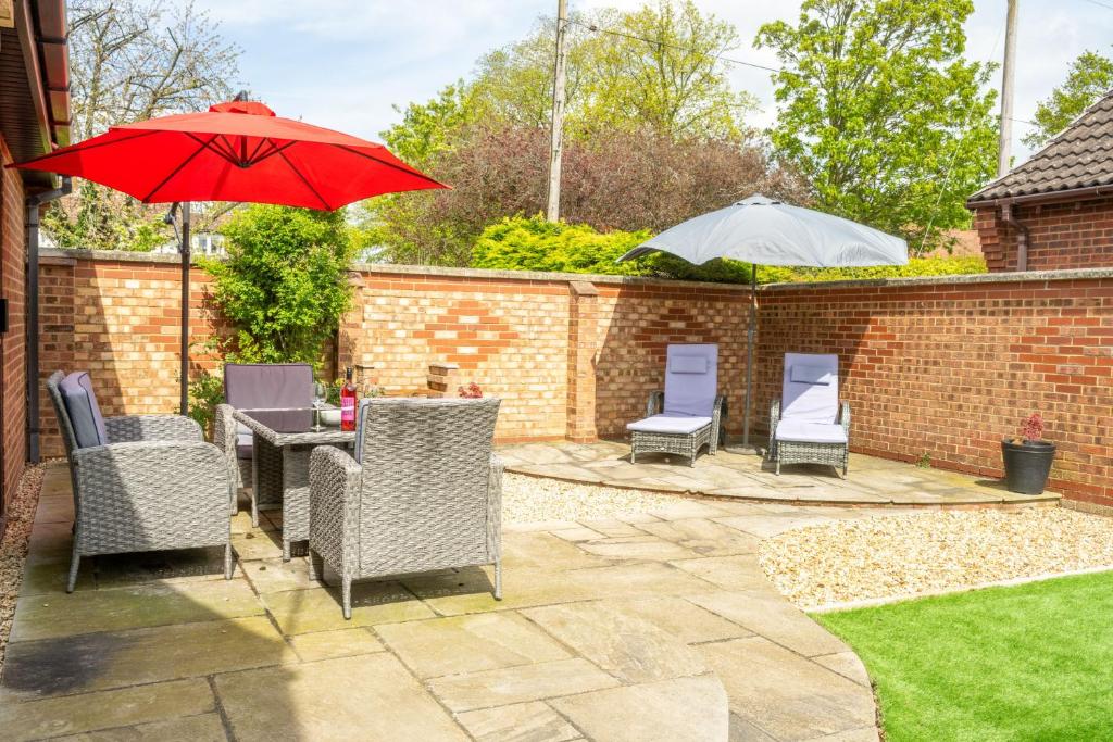 a patio with chairs and a table with a red umbrella at One Lazy Duck in Heacham