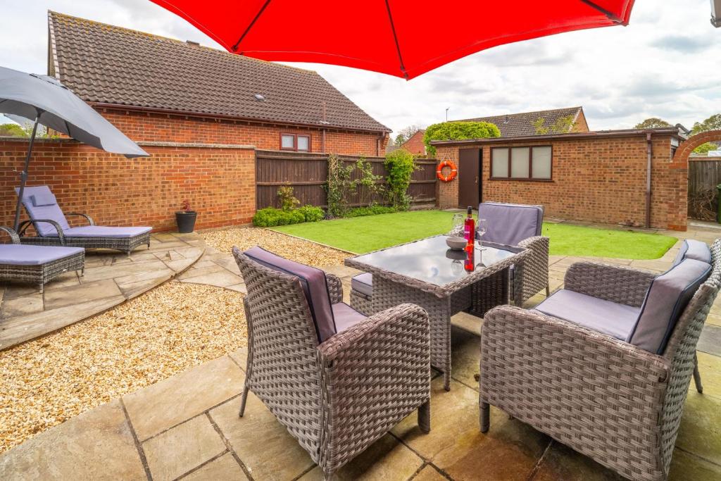 a patio with a table and chairs and a red umbrella at One Lazy Duck in Heacham