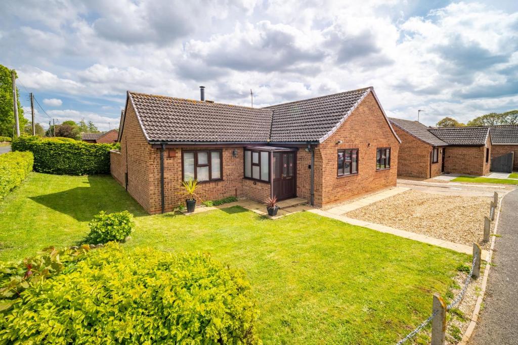 a brick house with a yard at One Lazy Duck in Heacham