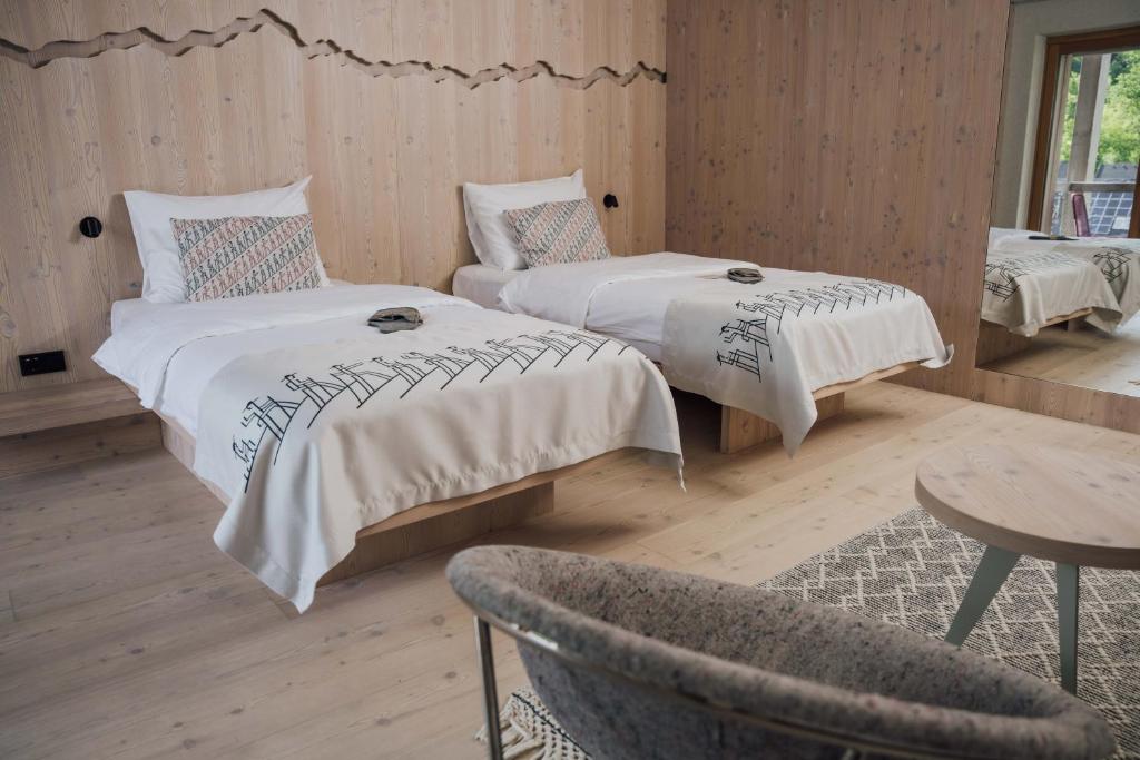 a room with two beds and a chair and a table at Hotel Bohinj in Bohinj
