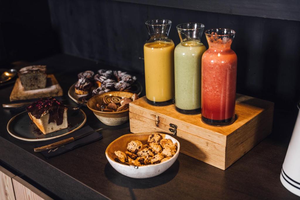 a table with three different colored drinks and a bowl of food at Hotel Bohinj in Bohinj